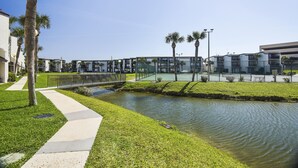 Un bâtiment moderne agrémenté d’un élément aquatique, d’un pont piétonnier et d’un aménagement paysager bien entretenu.