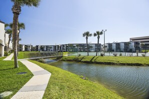 A modern building with a water feature, a pedestrian bridge, and well-maintained landscaping. - Sugar Beach by Book That Condo (Panama City Beach)