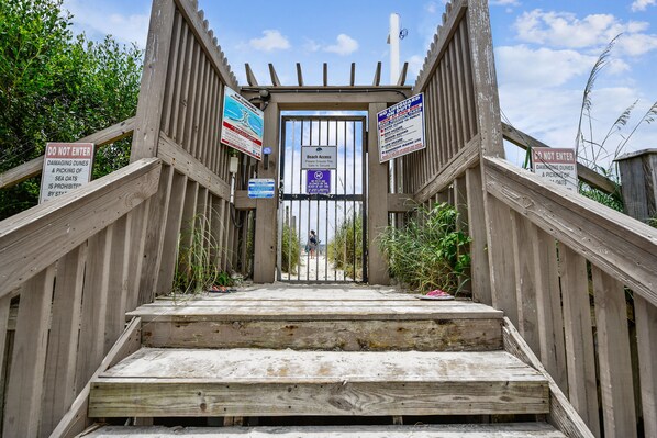 A wooden staircase leading to a beach gate with multiple warning signs. - Sugar Beach by Book That Condo (Panama City Beach)