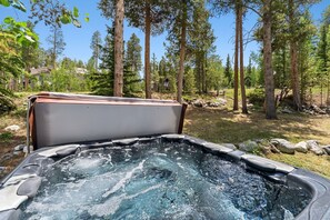 Ein Whirlpool inmitten eines bewaldeten Gebiets mit hoch aufragenden Bäumen und blauem Himmel.