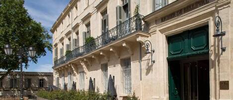 A historic building with a green door, a balcony with wrought iron railings, and a cobblestone courtyard.