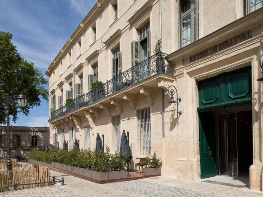 Un edificio histórico con puerta verde, balcón con barandilla de hierro forjado y un patio empedrado.