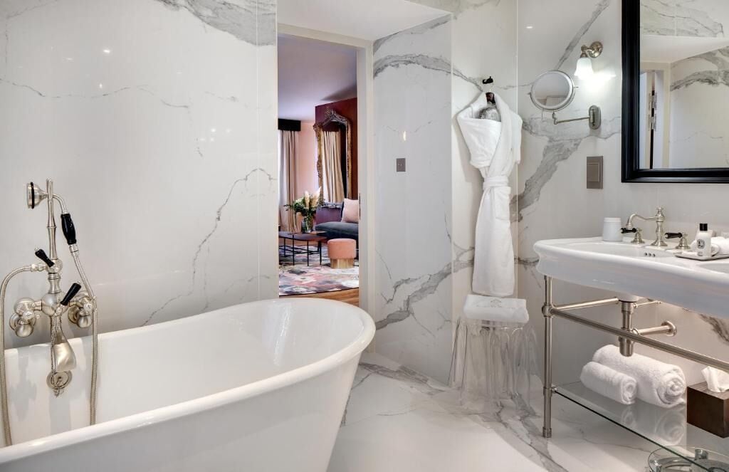 Une salle de bain moderne avec une baignoire sur pieds, un meuble-lavabo avec un miroir et des murs en marbre.