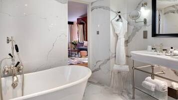 Une salle de bain moderne avec une baignoire sur pieds, un meuble-lavabo avec un miroir et des murs en marbre.