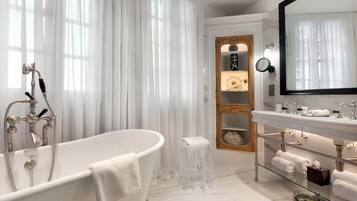 Une salle de bain moderne avec une baignoire sur pieds, un meuble-lavabo avec un miroir et une étagère avec des serviettes.