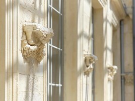Primer plano de la fachada de un edificio con elaboradas esculturas de piedra cerca de las ventanas.