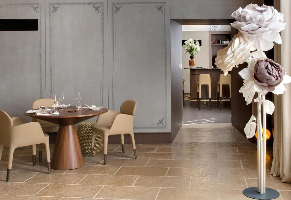 A dining area with a round table, chairs, and a decorative flower arrangement.