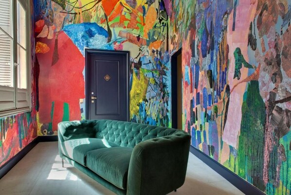 A room with a green sofa, a dark door, and colorful abstract wall art.