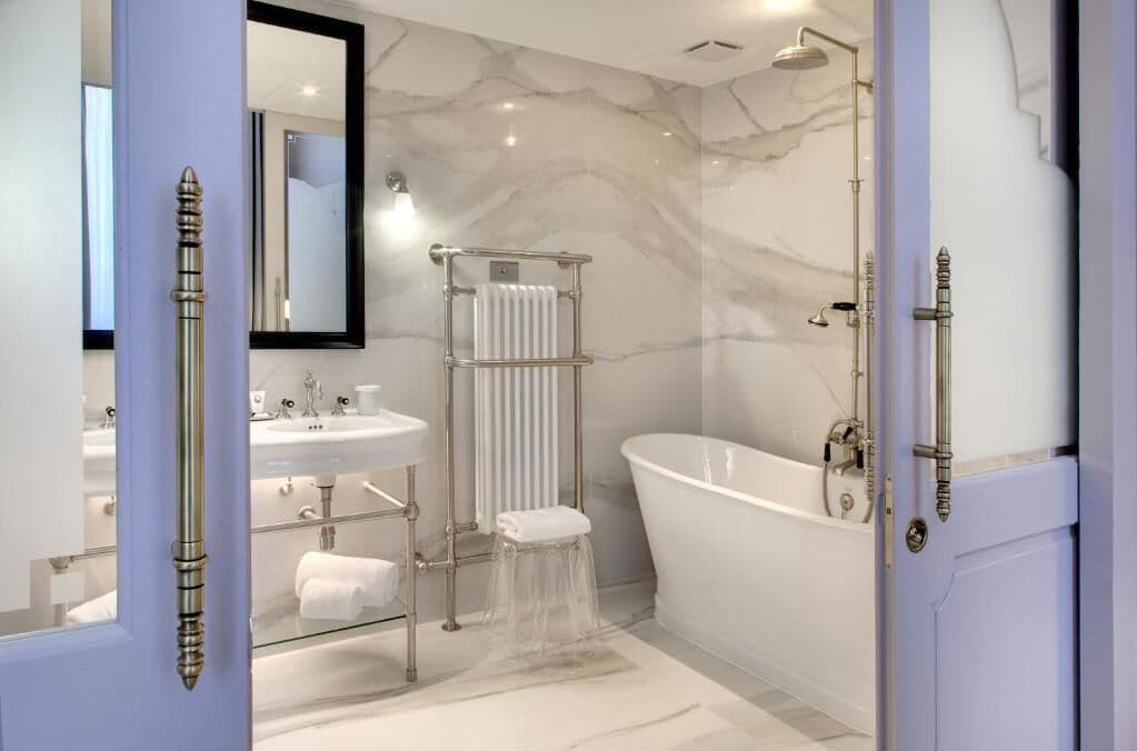 Une salle de bain moderne avec une baignoire sur pieds, une douche à parois de verre et un meuble-lavabo surmonté d’un plateau en marbre.