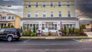A two-story building with a sign reading "ALLEHURST" and an American flag. - Cozy Studio 2 Blocks to Beach & Main Ave | Full Kitchen | Near Asbury Boardwalk (Ocean Grove)