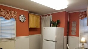 A compact kitchen with a white refrigerator, wooden cabinets, and a small dining area with a table and chair. - Pet Friendly 1st Floor Apt 2 Blocks to Beach & Main Ave | Private Entrance | ... (Ocean Grove)