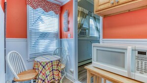 A compact kitchen with a microwave, a table with a checkered tablecloth, and a window with blinds. - Pet Friendly 1st Floor Apt 2 Blocks to Beach & Main Ave | Private Entrance | ... (Ocean Grove)