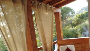 Una terraza de madera con una mesa, sillas, una planta en maceta y vistas a zonas verdes.
