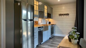A compact kitchen with a stainless steel refrigerator, built-in oven, and dishwasher. - Whitecaps Cabana for Couples (Riverport)