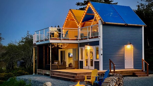 A two-story cabin with a balcony, a fire pit, and a stack of firewood. - Whitecaps Cabana for Couples (Riverport)