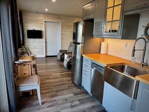 Eine kompakte Küche mit eingebautem Geschirrspüler, einem Edelstahlkühlschrank und einer Holz Arbeitsplatte.