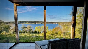 A covered outdoor seating area with a view of a lake and forest. - Whitecaps Cabana for Couples (Riverport)