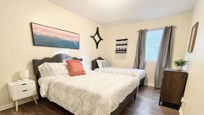 A bedroom with two beds, a nightstand, a dresser, a painting, and a window with curtains. - ★Pristine Pad ★ King Bed ★Duke ★ Long Term Stays★ (Durham)