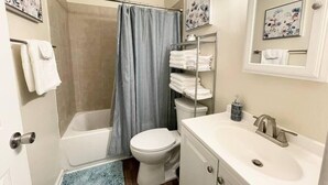 A bathroom with a bathtub, toilet, and sink. There are towels on a rack and a shower curtain. - ★Pristine Pad ★ King Bed ★Duke ★ Long Term Stays★ (Durham)