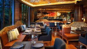 A restaurant with wooden walls, large windows, and a central decorative piece resembling a lobster. Tables are set with plates and glasses.