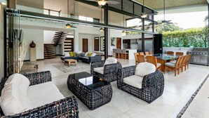 A spacious outdoor living area with wicker furniture, a glass-top table, and a kitchen area with modern appliances.