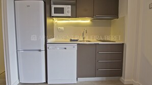 A compact kitchen with a refrigerator, microwave, dishwasher, and a sink with a faucet.