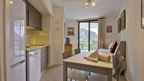 A compact kitchen with modern appliances, a dining area with a table and chairs, and a large window offering a view of the outdoors.