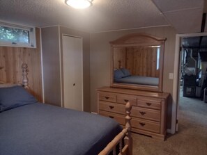 A bedroom with a bed, a dresser, a mirror, and a door.