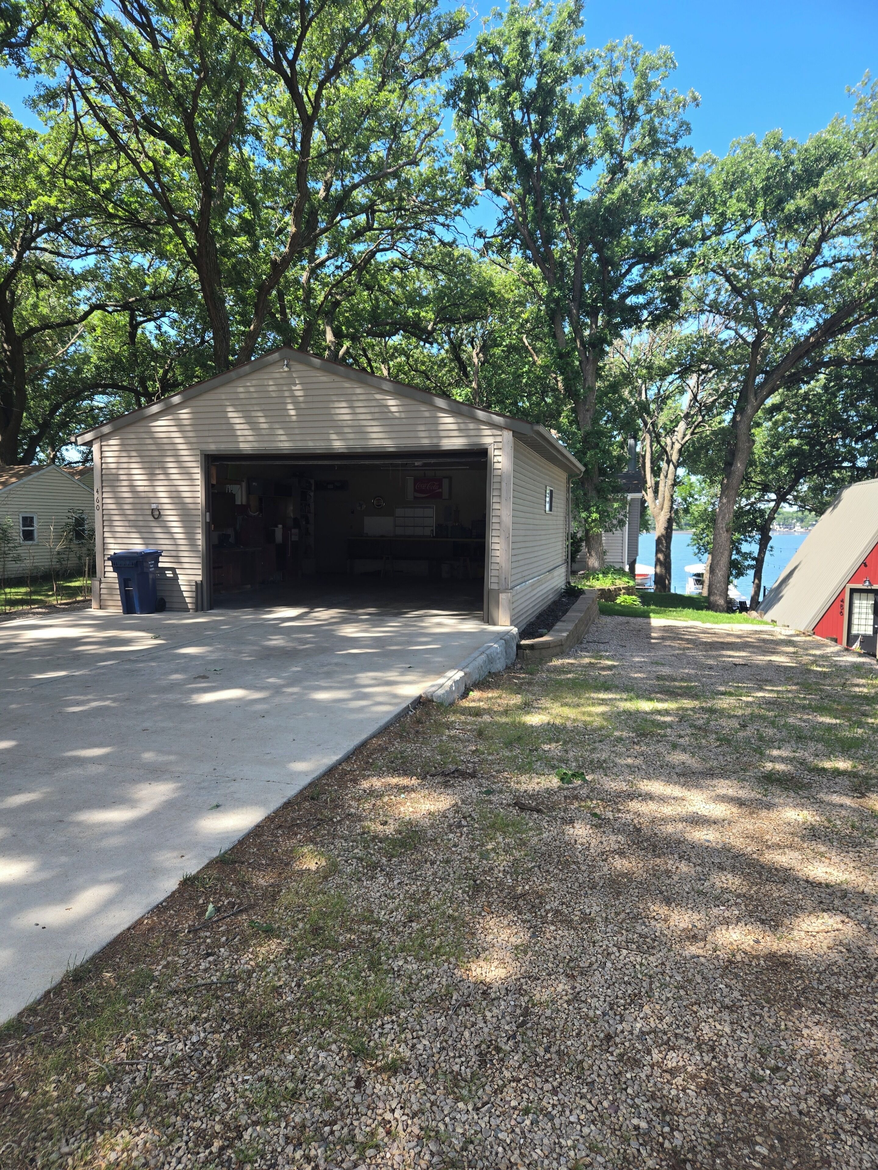 A single-story building with a garage, surrounded by trees and a gravel driveway.