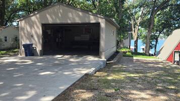 A single-story building with a garage, surrounded by trees and a gravel driveway.