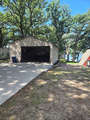 A single-story building with a garage, surrounded by trees and a gravel driveway.
