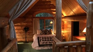 A cozy log cabin bedroom with a bed, a window, and a wooden railing. - DIRECT ACCESS TO TRAILS 5 and 8, SLEEPS 12, plus PRIVATE LAKE AND TRAILS (Champion)