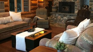 A cozy log cabin interior with a stone fireplace, wooden furniture, and a comfortable seating area. - DIRECT ACCESS TO TRAILS 5 and 8, SLEEPS 12, plus PRIVATE LAKE AND TRAILS (Champion)