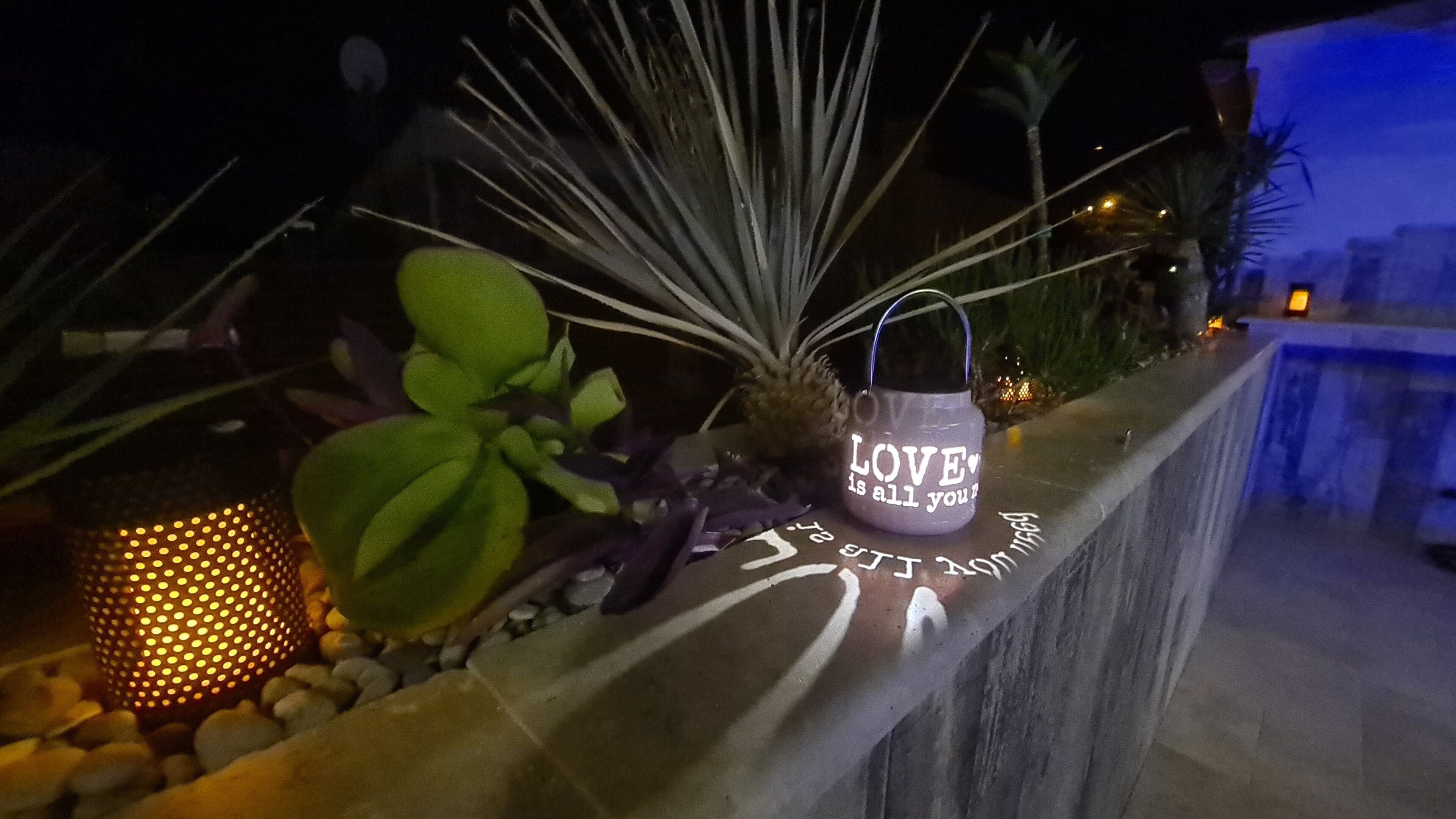 Un'area esterna decorata con un fioriere pieno di verde e un oggetto decorativo con la scritta “LOVE is all you need”.
