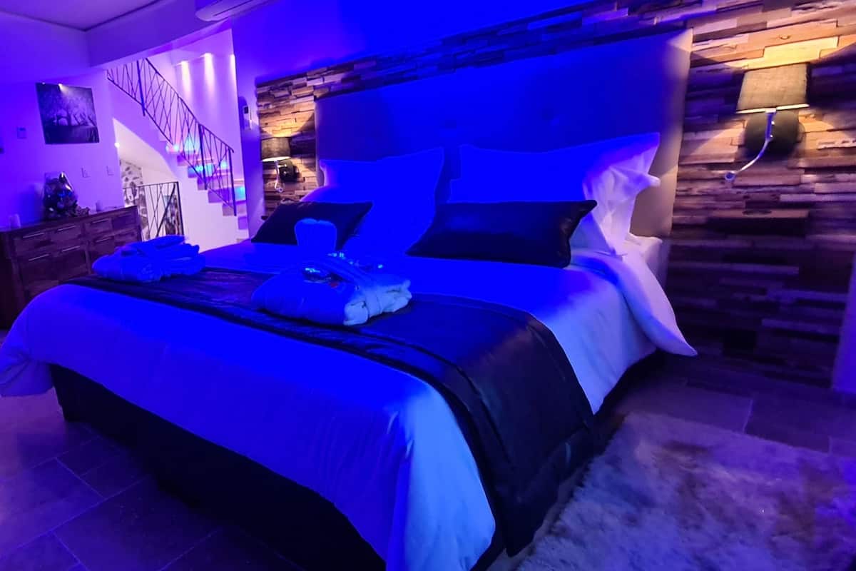 Un dormitorio con cama, cómoda, silla y escalera.
