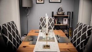 A dining table with a white candle centerpiece, black and white patterned chairs, and a bookshelf in the background. - Rose Apartment 2-bed Apt Town Centre Ayr (Ayr)