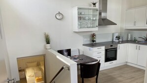 A modern kitchen with white cabinets, a built-in oven, and a coffee maker. - Apartment 1 city center, central, close to the beach and quiet (Norderney)
