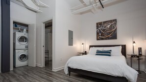 Ein Schlafzimmer mit einem großen Bett, einer Waschmaschine und einem Bild an der Wand.