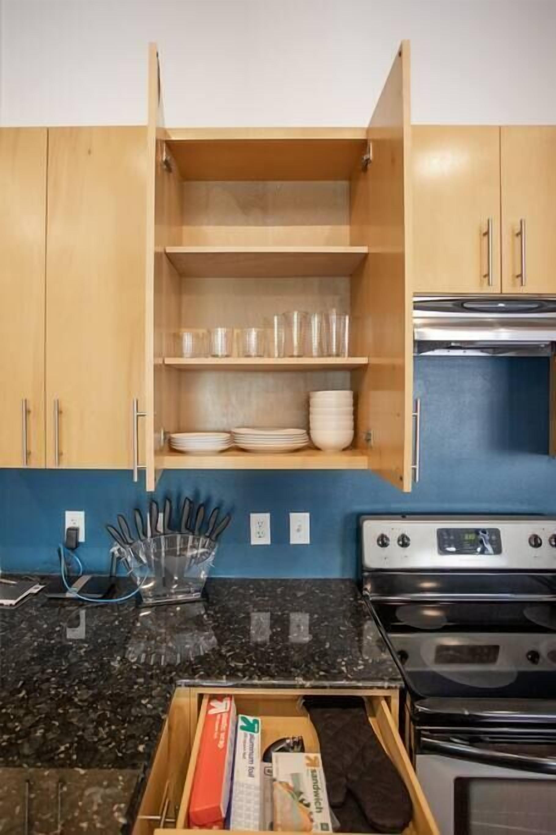 Eine Küche mit Holzausstattung, einer Arbeitsplatte aus Granit, einem Herd und einer Mikrowelle.