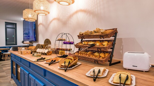 A breakfast buffet with various breads, pastries, and a toaster. - Hôtel Le Cyrano (Bergerac)