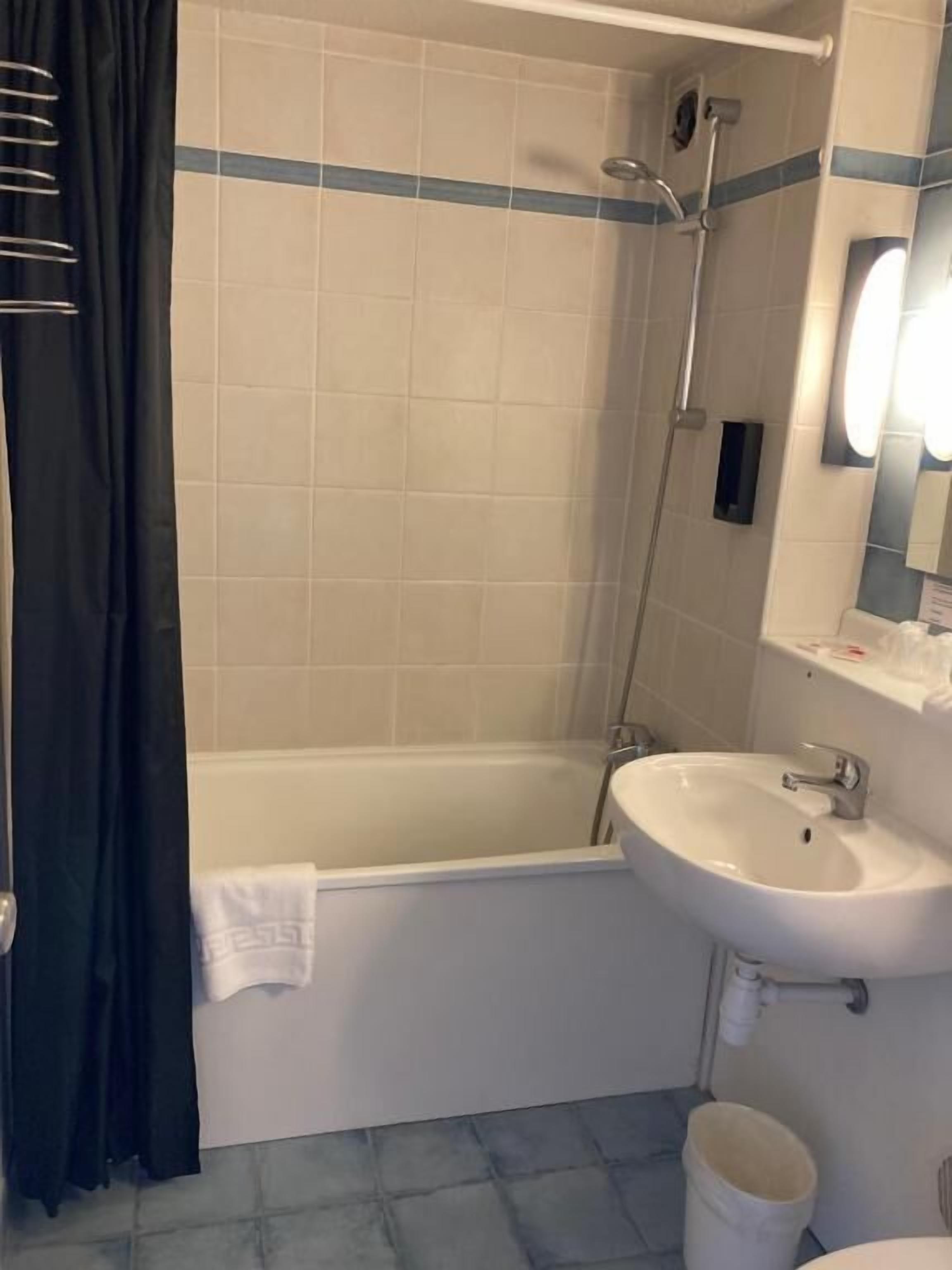 A bathroom with a bathtub, a sink, a shower, and a mirror.