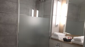 A modern bathroom with a glass-enclosed shower, a white sink, and a toilet. - Hôtel Le Cyrano (Bergerac)