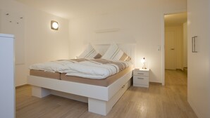 A modern bedroom with a bed, bedside table, and a nightstand. - Apartment 2 City center, central, close to the beach and quiet (Norderney)