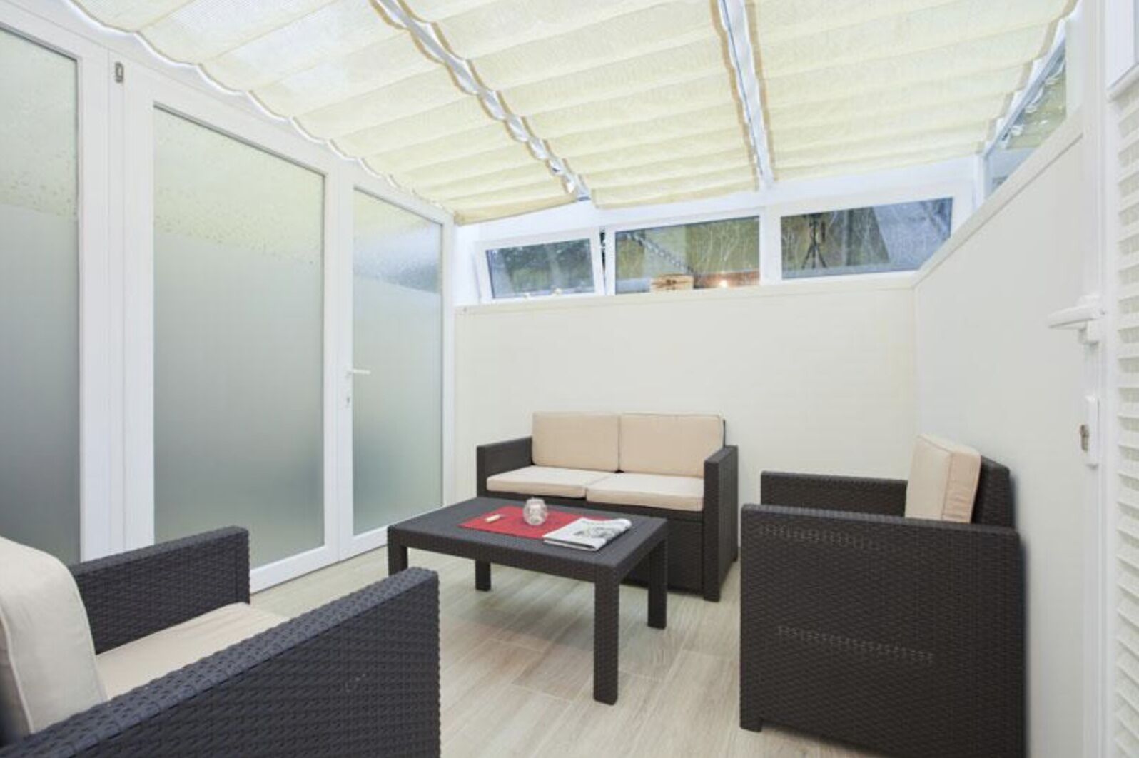 A covered patio area with wicker furniture, a sofa, and a table.