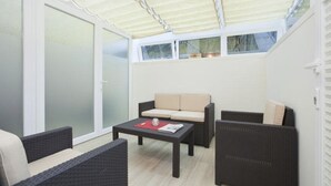 A covered patio area with wicker furniture, a sofa, and a table. - Apartment 2 City center, central, close to the beach and quiet (Norderney)