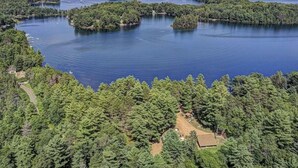 Une vue aérienne d’un lac entouré d’une forêt dense, avec plusieurs petites îles et quelques bâtiments visibles.