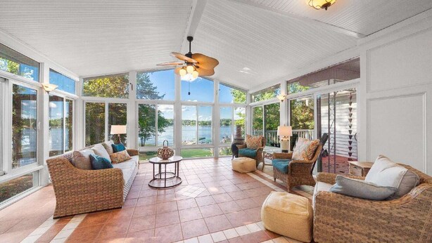 A spacious sunroom with large windows, wicker furniture, and a ceiling fan. - Relaxing Waterfront w/ Dock, Easy Drive, On the Lake (Eatonton)