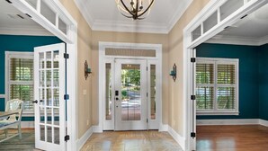 A spacious hallway with a double door, a chandelier, and a view of the outdoors. - Relaxing Waterfront w/ Dock, Easy Drive, On the Lake (Eatonton)