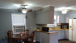 Una cocina con una mesa de comedor y sillas, un ventilador de techo y un refrigerador.