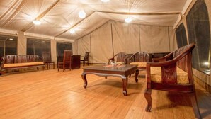 A tented room with wooden furniture, including a sofa and chairs, and a table. - Lorian Safari Camp (Maasai Mara)